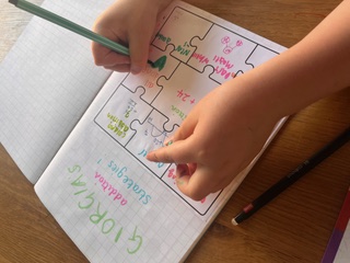 A child writing personalised addition strategies in a workbook during a session